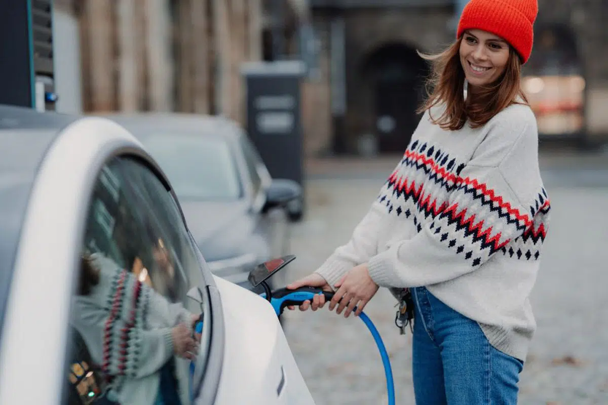 Woman in orange hat charging electric car