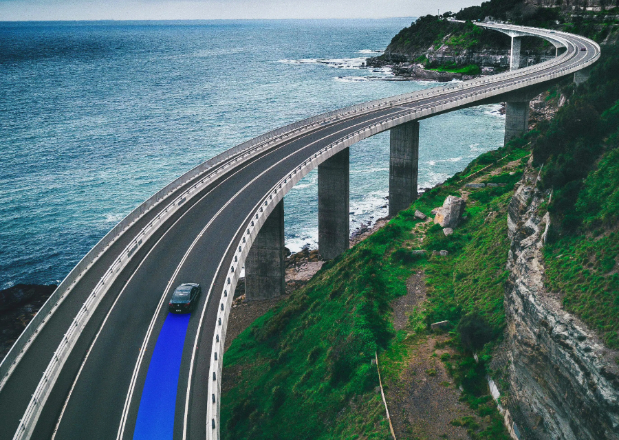 Electric car drives on road over water with blue gradient